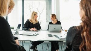Fyra kollegor i möte på kontor – diskuterar bemanning och rekrytering vid konferensbord med laptops